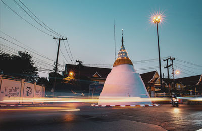 Light trails on street against sky at dusk