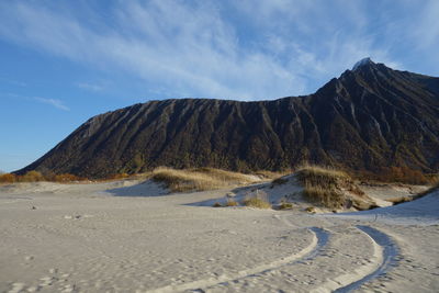Scenic view of sand dunes and mountains against sky