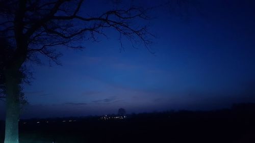 Silhouette landscape against blue sky at night