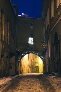 Empty road amidst buildings in city at night