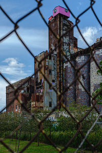 Chainlink fence by building against sky