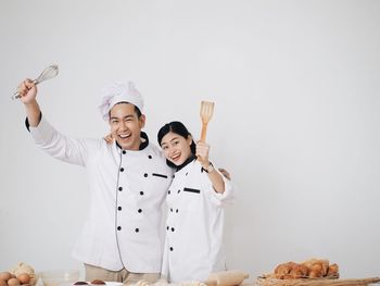 Portrait of smiling male and female chef against white background