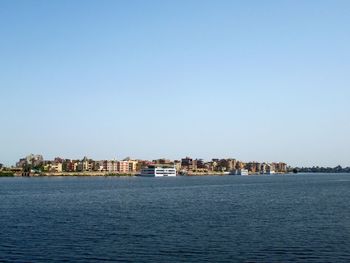 Sea by buildings against clear blue sky