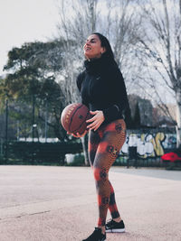 Full length of woman with ball while standing on tree