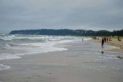 People walking on beach against sky