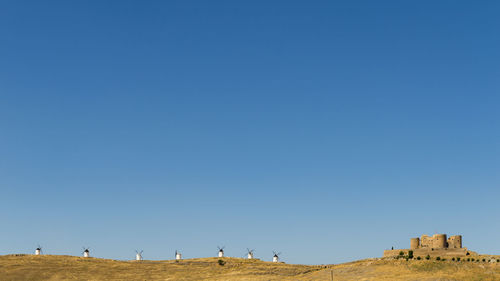 Panoramic view of people on land against clear blue sky
