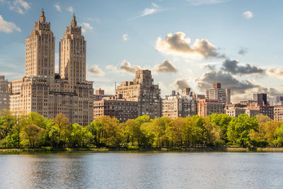 Buildings by river against sky