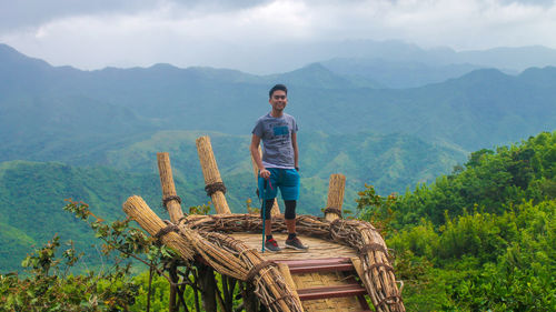 Portrait of man standing on observation point on mountain against sky