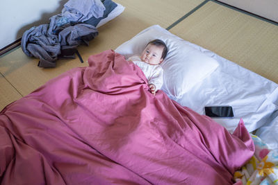 High angle view of baby relaxing on bed at home