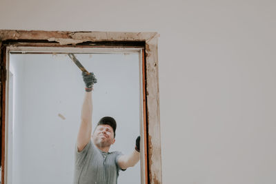 A man working with a crowbar in a doorway.