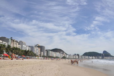 People on beach against buildings in city