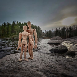 Rear view of women on rocks at shore against sky