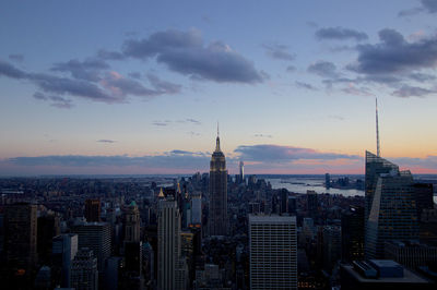 Modern buildings in city against sky during sunset