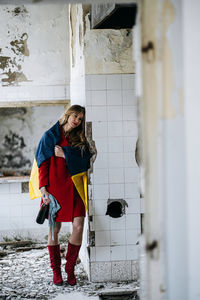 Side view of young woman standing against wall