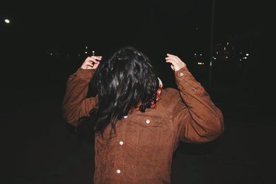 Rear view of woman standing against black background