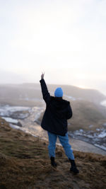 Rear view of man standing on mountain against sky during sunset