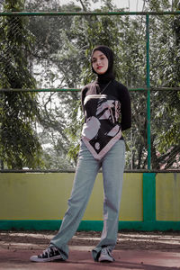 Portrait of teenage girl standing against tree