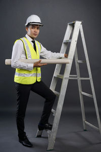 Portrait of man standing against ladder