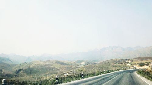 Road passing through mountains against clear sky
