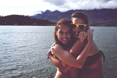 Portrait of happy friends hugging by lake