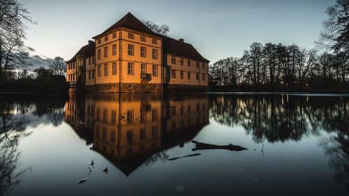 Reflection of building in lake against sky