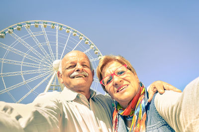 Low angle view of people in amusement park against sky