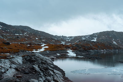 Scenic view of lake by snowcapped mountains against sky