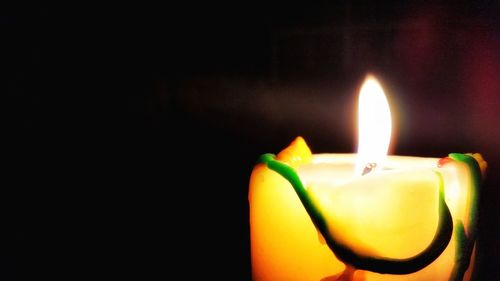 Close-up of lit candle against black background