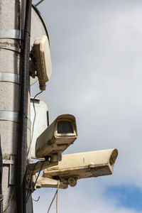 Two old cctv security surveillance cameras on street light pole on blue sky background