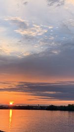 Scenic view of sea against dramatic sky during sunset