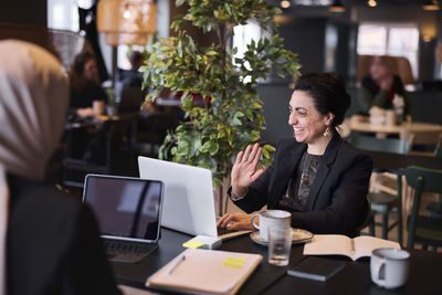 Smiling businesswoman using laptop in cafe