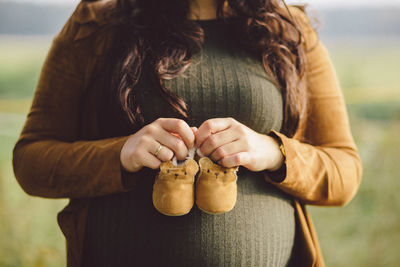 Midsection of pregnant woman holding shoes