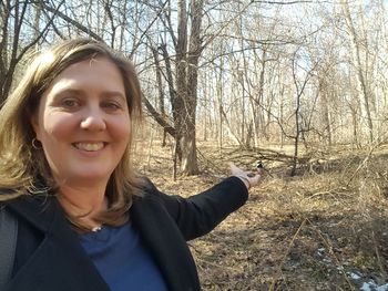 Portrait of smiling young woman standing on bare tree