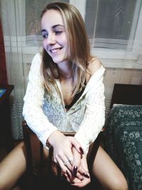 Portrait of smiling young woman sitting at home
