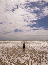 Rear view of man on beach against sky