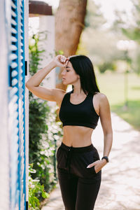 Side view of young woman standing against sky