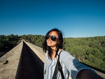 Portrait of smiling woman against clear blue sky