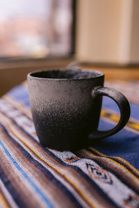 A rustic coffee mug on top of an aguayo tablecloth