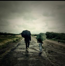 Rear view of people walking on road during rainy season