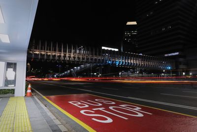 Illuminated road sign on street in city at night