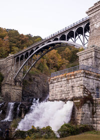 Arch bridge over river against sky