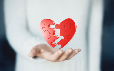 Digital composite image of woman holding heart shape jigsaw puzzle