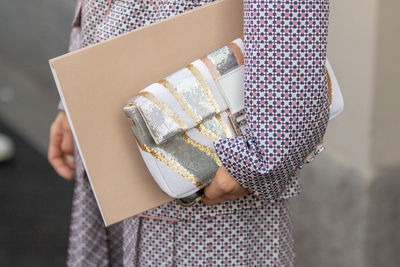 Midsection of woman holding purse and file