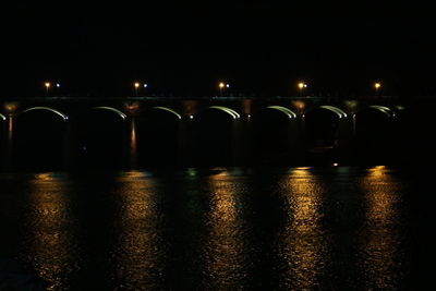 Illuminated bridge over river at night