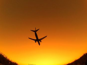 Silhouette airplane against clear sky during sunset