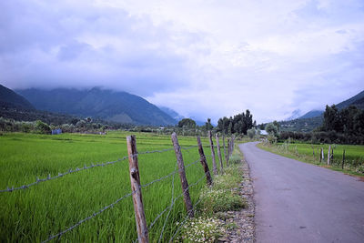 Road amidst field against sky