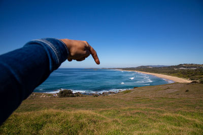 Midsection of man on beach against clear blue sky