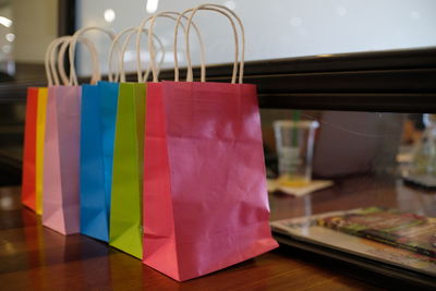 Close-up of colorful shopping bags in row on wooden table