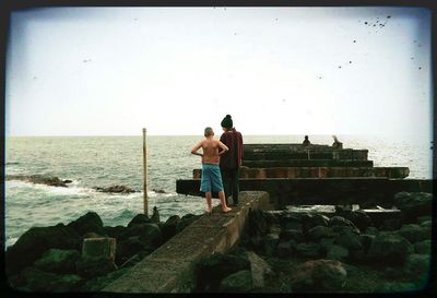 Men standing on beach against sky