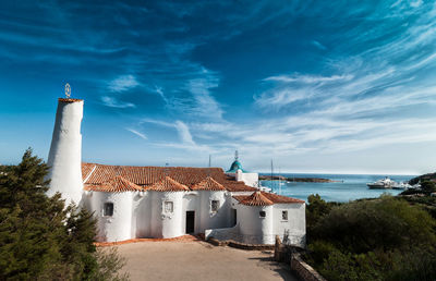 Buildings by sea against blue sky